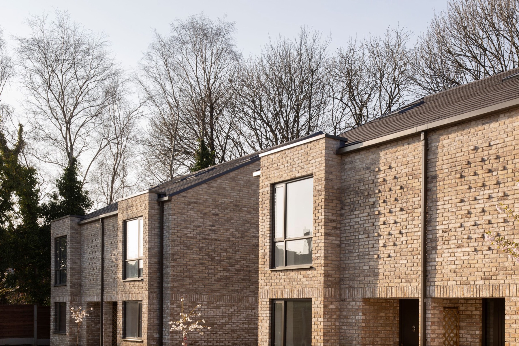 Brick and stone townhouses at Lawn Drive, Whalley Range, framed by mature trees